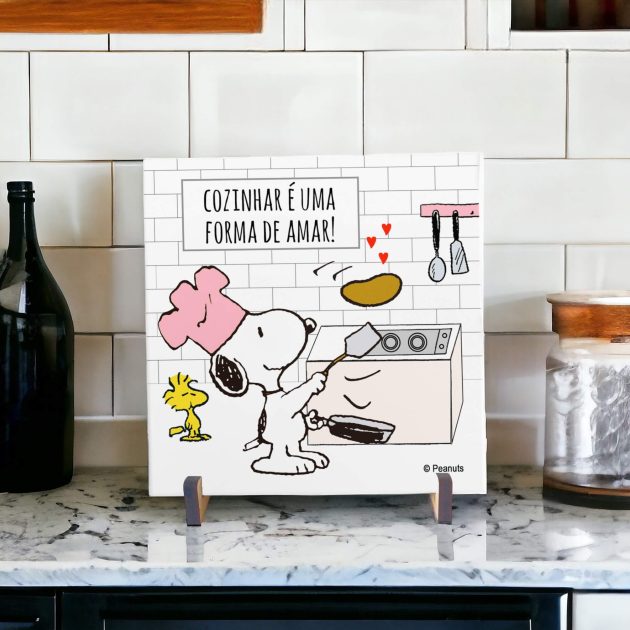 Azulejo decorativo para cozinha com desenho do Snoopy e Woodstock em uma cozinha fazendo panquecas com a frase "Cozinhar é uma forma de amar"