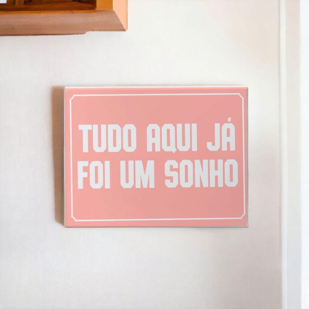 Azulejo decorativo com a frase Tudo aqui já foi um sonho com o fundo rosa