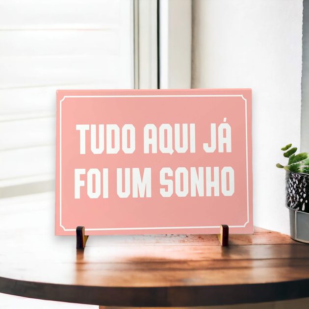 Azulejo decorativo com a frase Tudo aqui já foi um sonho com o fundo rosa