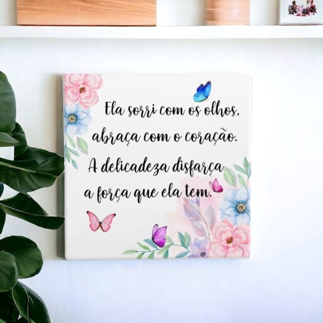 Azulejo decorativo com a frase Ela sorri com os olhos, abraça com o coração. A delicadeza disfarça a força que ela tem