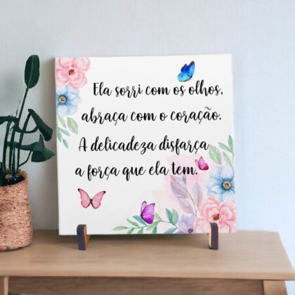 Azulejo decorativo com a frase Ela sorri com os olhos, abraça com o coração. A delicadeza disfarça a força que ela tem